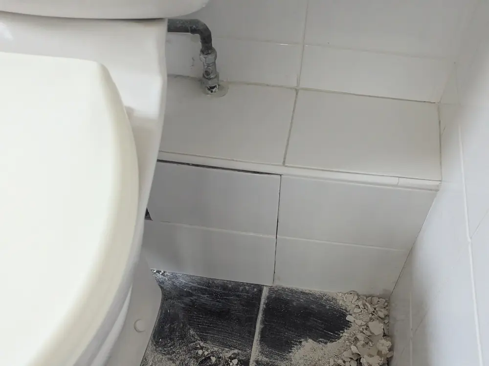 Damaged bathroom floor around a toilet before the repair